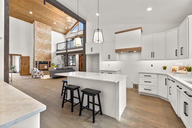 kitchen with light stone counters, decorative light fixtures, a center island, and white cabinets