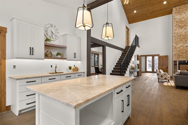 kitchen with hanging light fixtures, a kitchen island, white cabinets, and high vaulted ceiling