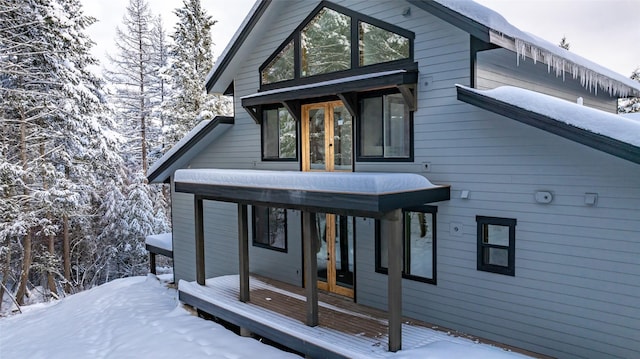 snow covered back of property with french doors