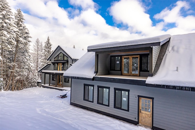 snow covered rear of property with french doors