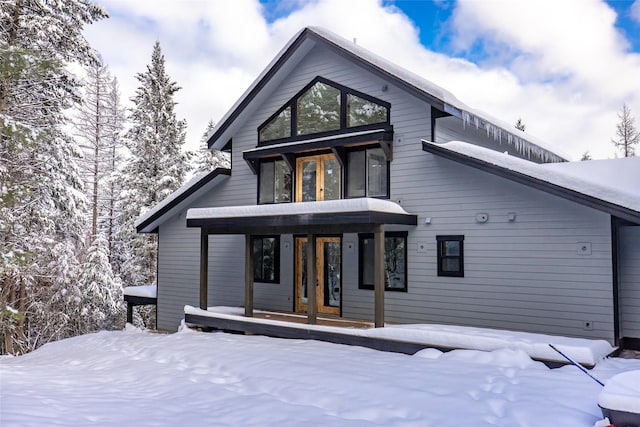 snow covered house featuring covered porch