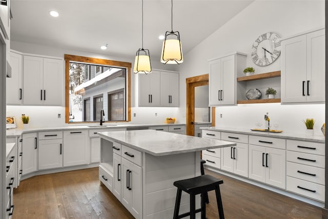 kitchen featuring dark hardwood / wood-style flooring, a center island, vaulted ceiling, and white cabinets