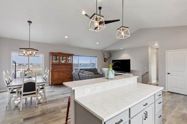 kitchen with pendant lighting, lofted ceiling, a center island, light hardwood / wood-style floors, and white cabinets