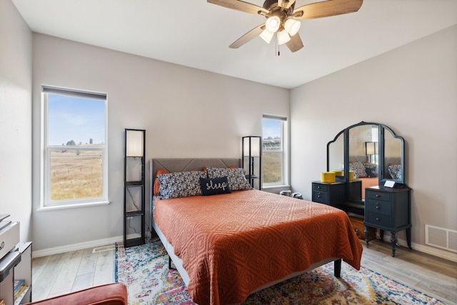 bedroom with ceiling fan, light hardwood / wood-style floors, and multiple windows