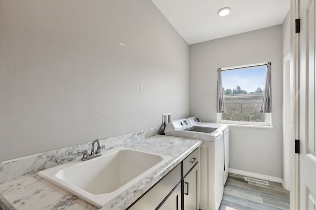 clothes washing area with cabinets, light hardwood / wood-style floors, sink, and washing machine and dryer