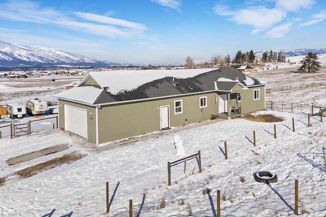 snow covered rear of property featuring a garage and a mountain view