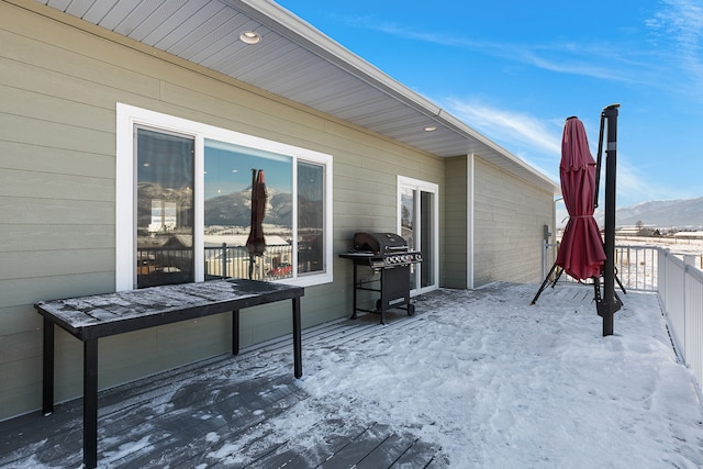 snow covered deck featuring a mountain view and a grill