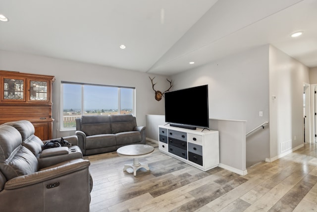 living room featuring lofted ceiling and light hardwood / wood-style floors