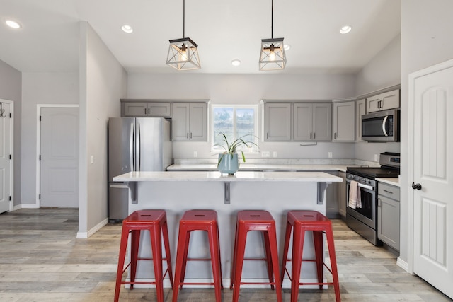 kitchen with appliances with stainless steel finishes, hanging light fixtures, a kitchen island, and gray cabinetry