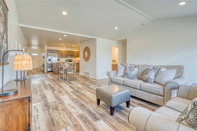 living room featuring vaulted ceiling with beams and light wood-type flooring