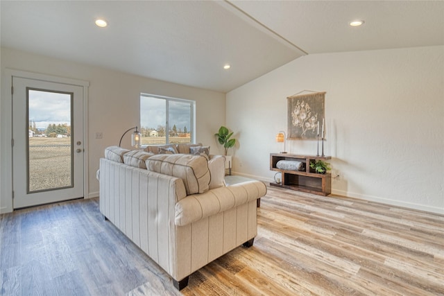 living room with light hardwood / wood-style flooring, plenty of natural light, and vaulted ceiling