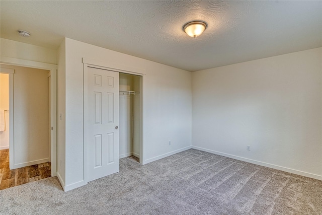 unfurnished bedroom featuring a closet, light carpet, and a textured ceiling