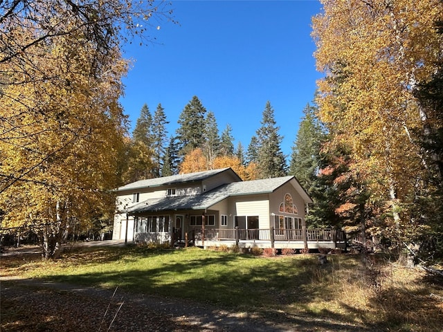 rear view of house with a wooden deck and a lawn