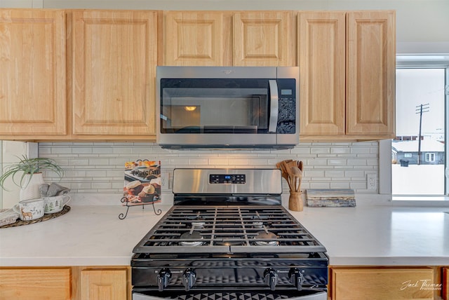 kitchen with light brown cabinetry, backsplash, and stainless steel appliances