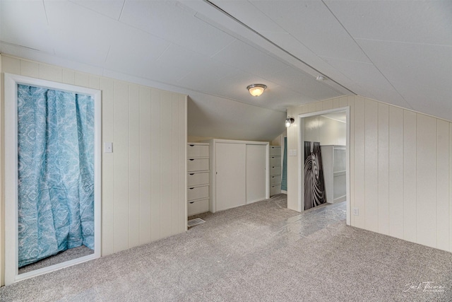 bonus room with vaulted ceiling, wooden walls, and carpet floors