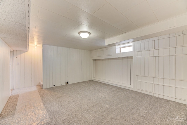 basement featuring carpet and wooden walls