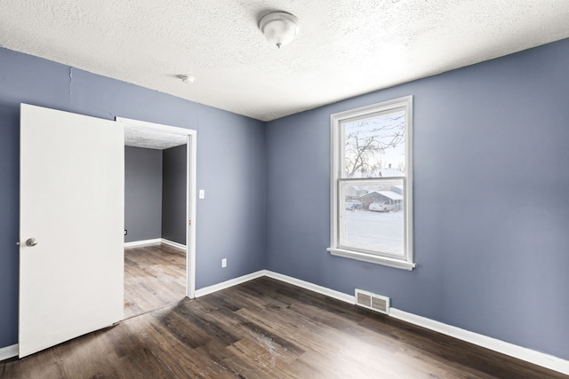 empty room featuring dark wood-type flooring and a textured ceiling