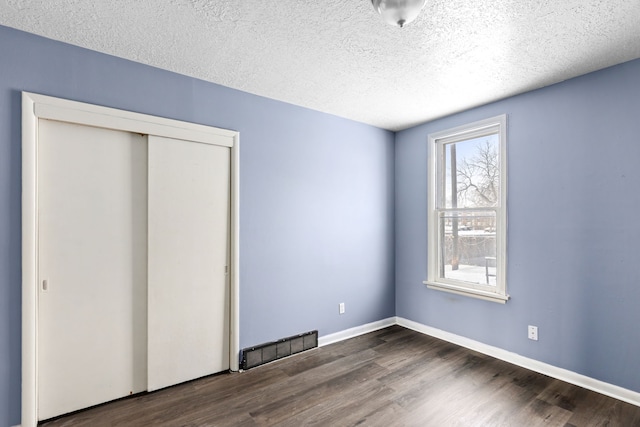 unfurnished bedroom featuring dark wood-type flooring, a closet, and a textured ceiling