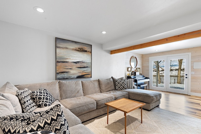 living room featuring wood walls, beam ceiling, and light hardwood / wood-style flooring