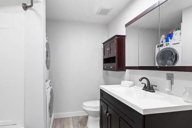 bathroom with vanity, wood-type flooring, toilet, and stacked washer / dryer