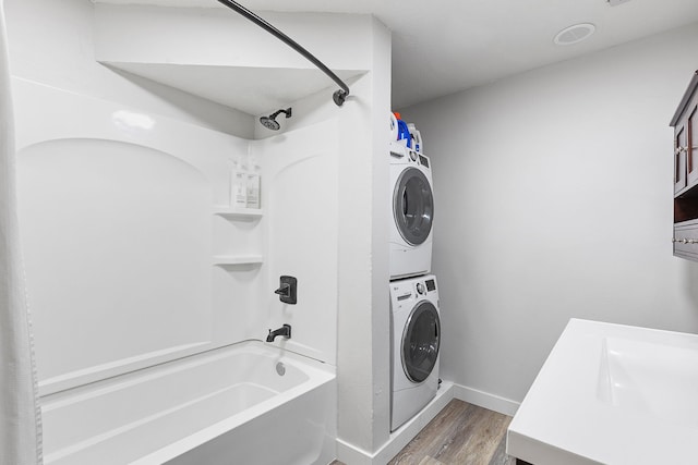 clothes washing area with stacked washer / drying machine and wood-type flooring