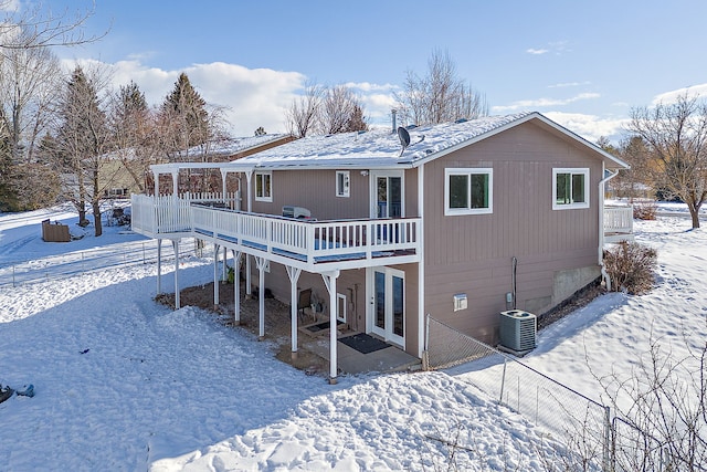 snow covered house featuring central AC unit and a deck