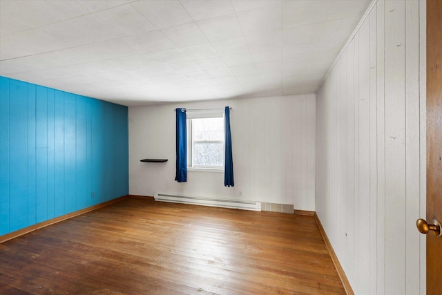 empty room featuring wood-type flooring and baseboard heating