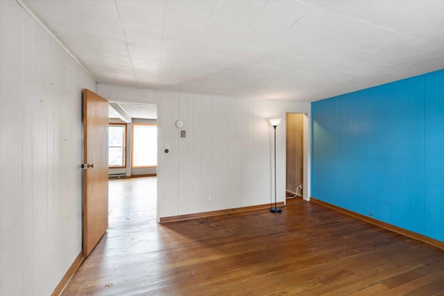 unfurnished room with hardwood / wood-style flooring and a baseboard heating unit