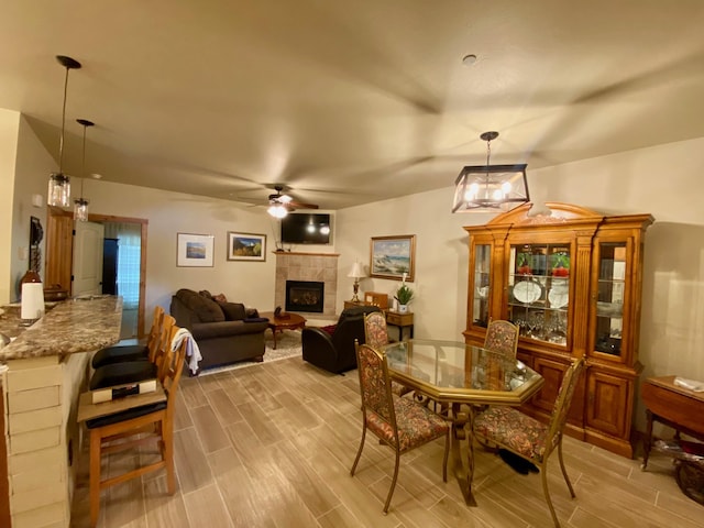 dining space featuring ceiling fan and a tile fireplace