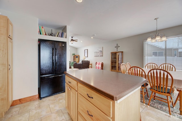 kitchen featuring hanging light fixtures, black fridge, a center island, and light brown cabinetry