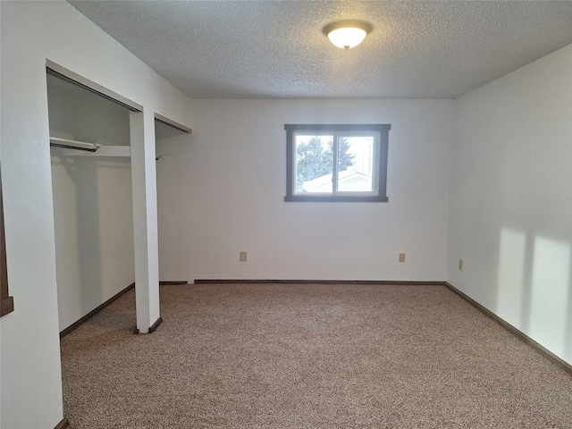 unfurnished bedroom with baseboards, a textured ceiling, carpet, and multiple closets