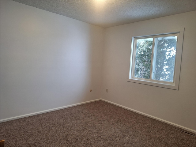 spare room with carpet, visible vents, a textured ceiling, and baseboards