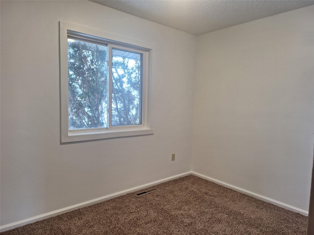 unfurnished room featuring carpet flooring, visible vents, baseboards, and a textured ceiling