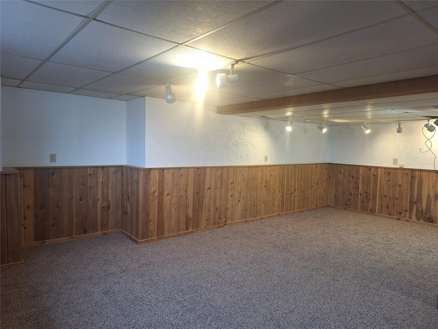 finished basement with carpet, a drop ceiling, wainscoting, and wooden walls