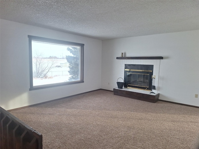 unfurnished living room with a textured ceiling, carpet floors, a fireplace, and baseboards