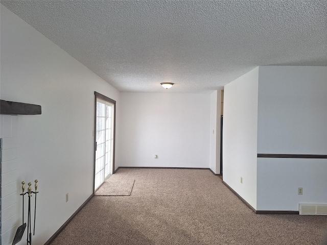 empty room with carpet, a textured ceiling, visible vents, and baseboards