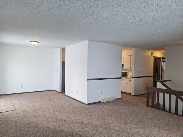 unfurnished room featuring visible vents, dark carpet, a textured ceiling, and baseboards