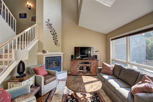 living room with a large fireplace, hardwood / wood-style floors, and high vaulted ceiling