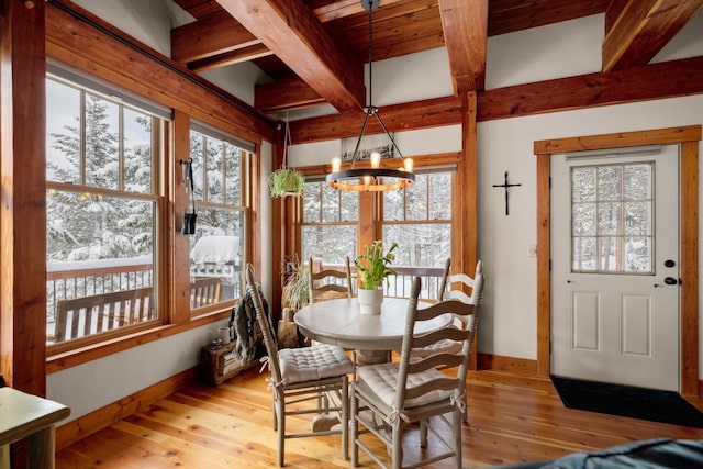 sunroom featuring beamed ceiling, a wealth of natural light, and an inviting chandelier