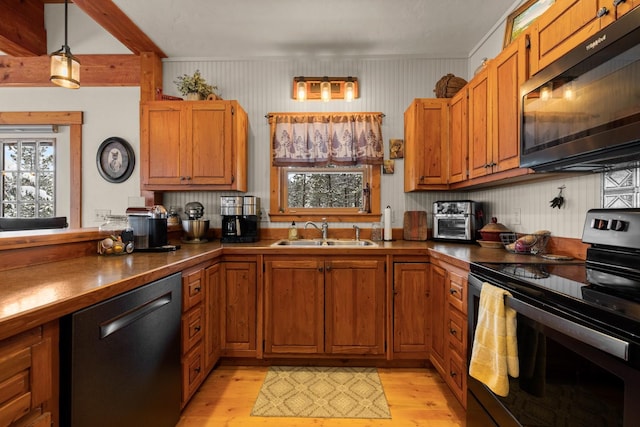 kitchen featuring sink, pendant lighting, light wood-type flooring, and black appliances