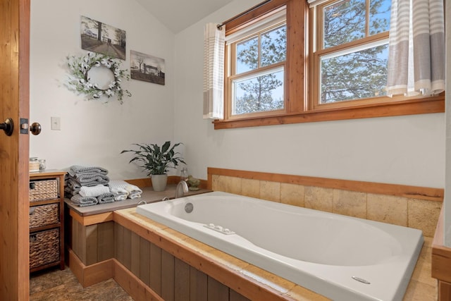 bathroom with a tub to relax in and vaulted ceiling