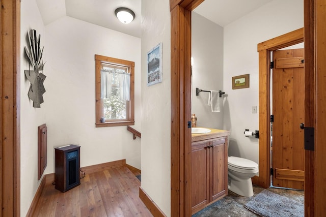 bathroom featuring hardwood / wood-style flooring, vanity, lofted ceiling, and toilet