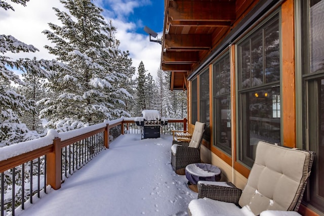 snow covered deck with a grill