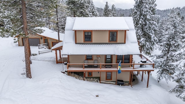 snow covered back of property featuring a wooden deck