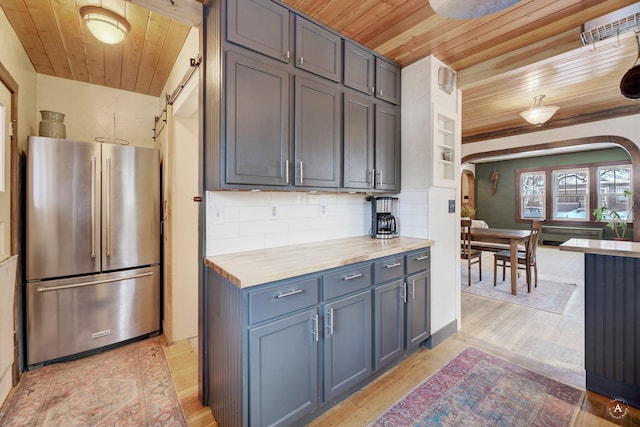 kitchen with wooden ceiling, wooden counters, stainless steel fridge, and backsplash