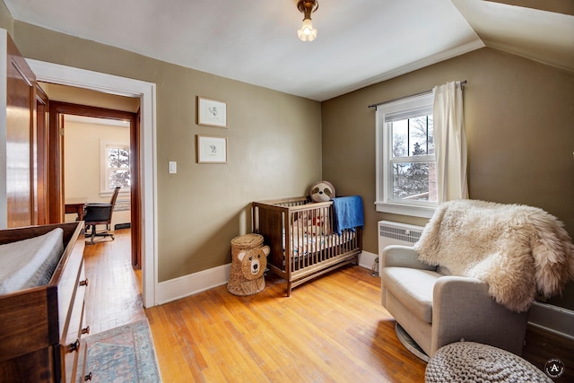 bedroom with multiple windows, radiator, vaulted ceiling, and light wood-type flooring