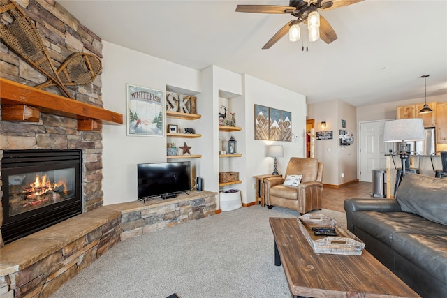 living room featuring carpet flooring, baseboards, ceiling fan, and a fireplace