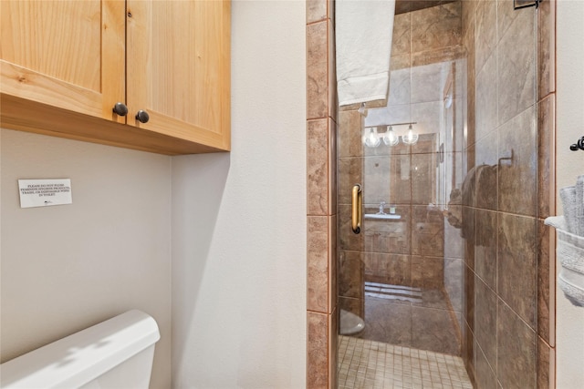 bathroom featuring toilet and a shower with door