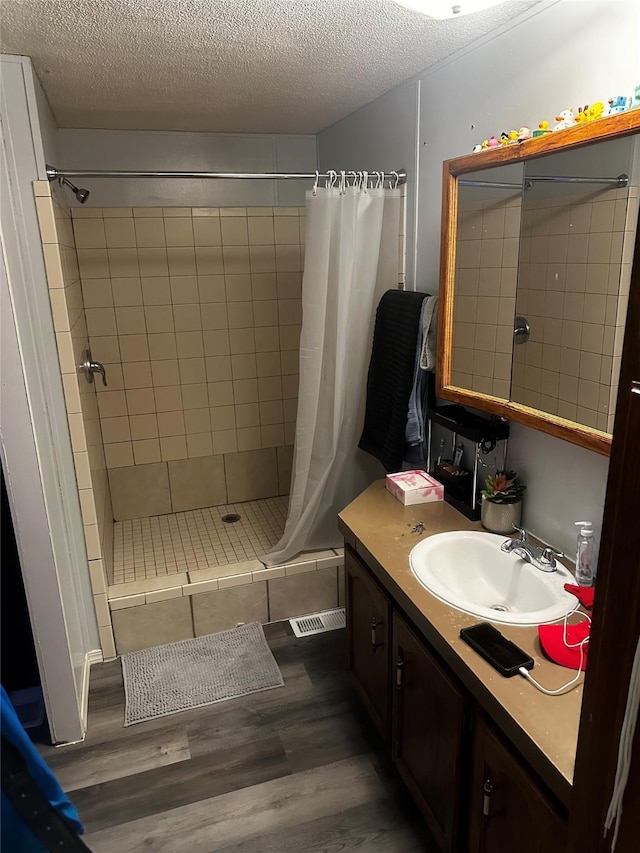 bathroom featuring walk in shower, vanity, a textured ceiling, and hardwood / wood-style flooring