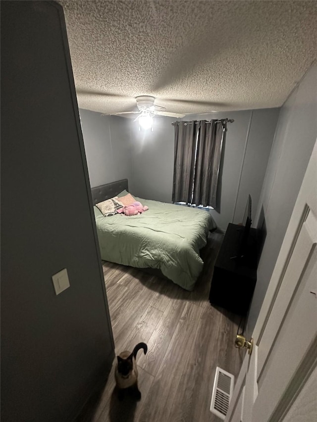 bedroom featuring ceiling fan, hardwood / wood-style floors, and a textured ceiling